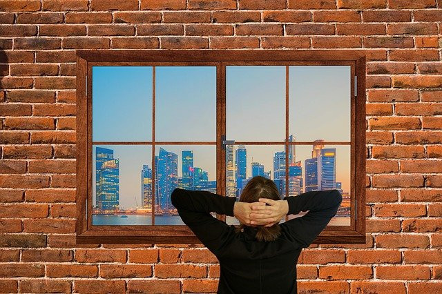 Lady Standing In Front Of The Window Staring Out AT The City Life